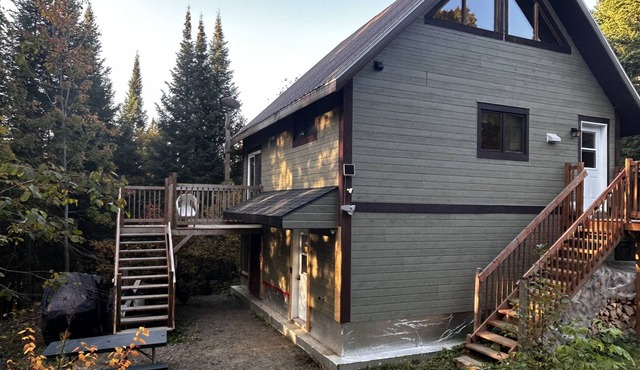 A cozy rustic mountain side cabin with a small river on the property.
